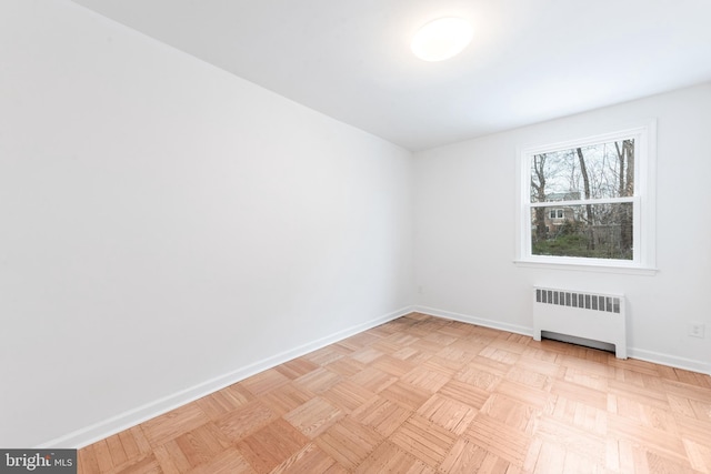 spare room with radiator heating unit and light parquet floors