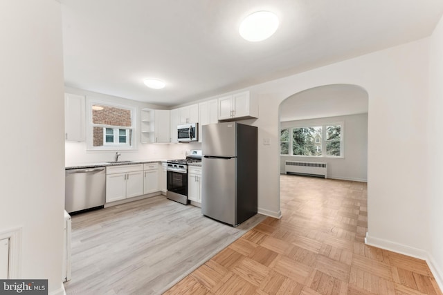 kitchen featuring sink, white cabinets, radiator, and stainless steel appliances