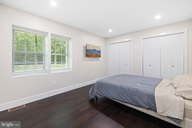 bedroom with dark wood-type flooring and multiple closets