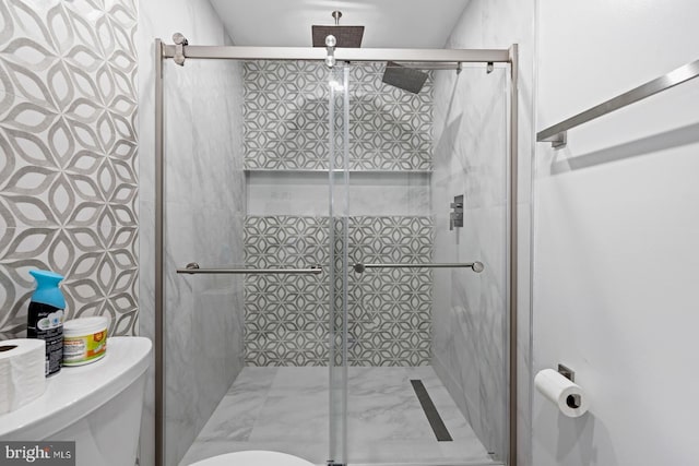 bathroom with a shower with shower door and toilet