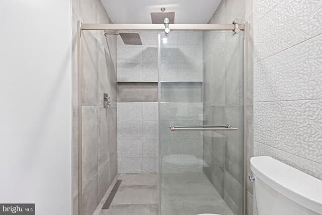 bathroom featuring toilet, tile walls, and walk in shower