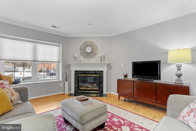 living room with light hardwood / wood-style flooring, ornamental molding, and a premium fireplace