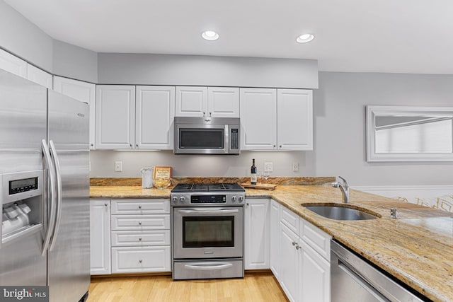 kitchen featuring appliances with stainless steel finishes, white cabinetry, and sink