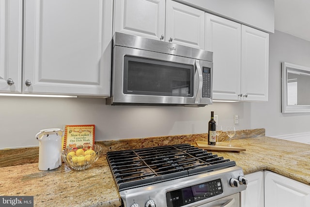 kitchen featuring white cabinets, appliances with stainless steel finishes, and light stone counters