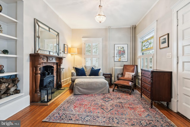 living area with radiator, a healthy amount of sunlight, and hardwood / wood-style floors