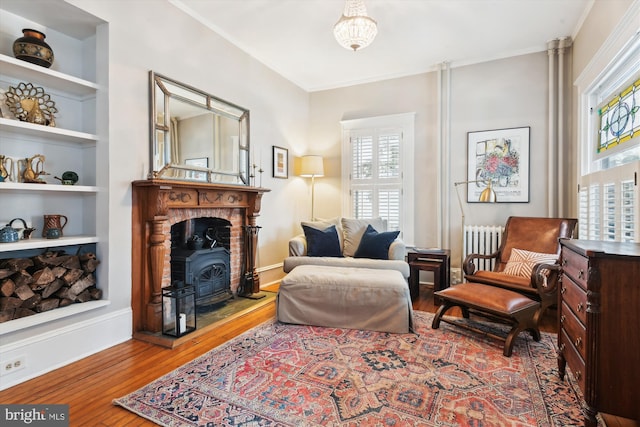 sitting room featuring built in shelves, radiator heating unit, and wood-type flooring