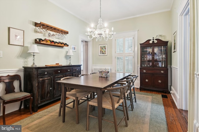 dining room featuring ornamental molding, an inviting chandelier, radiator, and dark hardwood / wood-style flooring