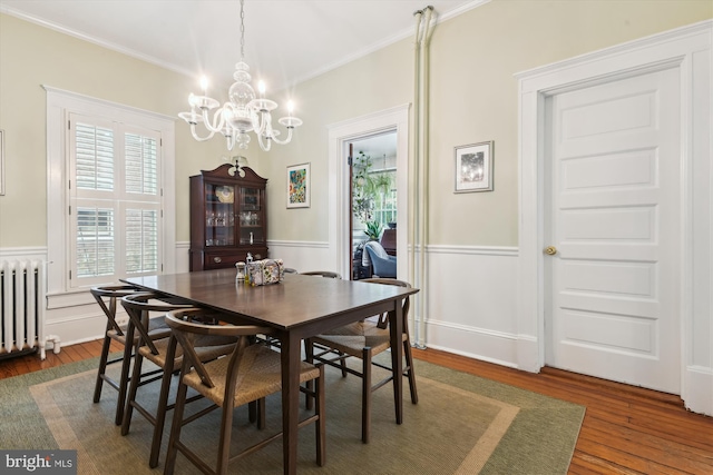 dining room featuring radiator heating unit, dark wood-type flooring, a notable chandelier, and ornamental molding