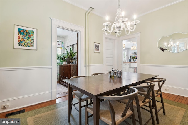 dining area featuring dark hardwood / wood-style flooring, ornamental molding, and a notable chandelier