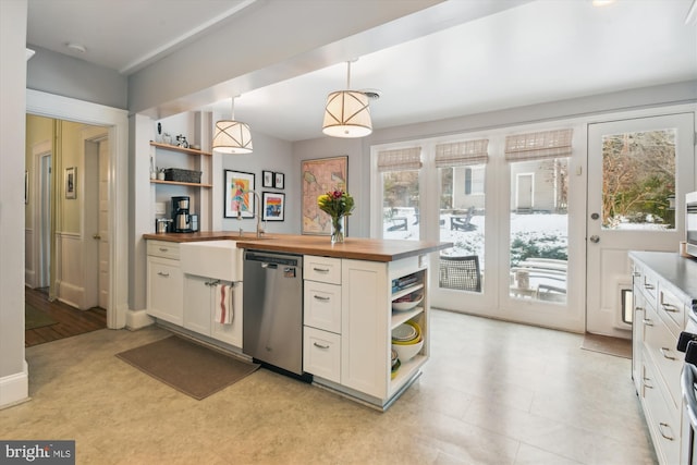 kitchen featuring wooden counters, stainless steel dishwasher, white cabinets, sink, and pendant lighting