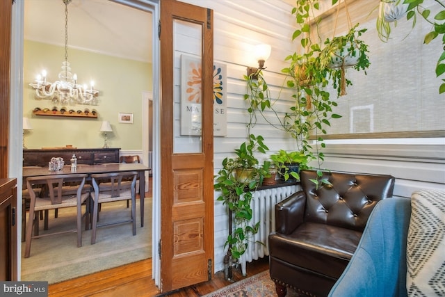 interior space featuring a chandelier, radiator heating unit, ornamental molding, and hardwood / wood-style floors