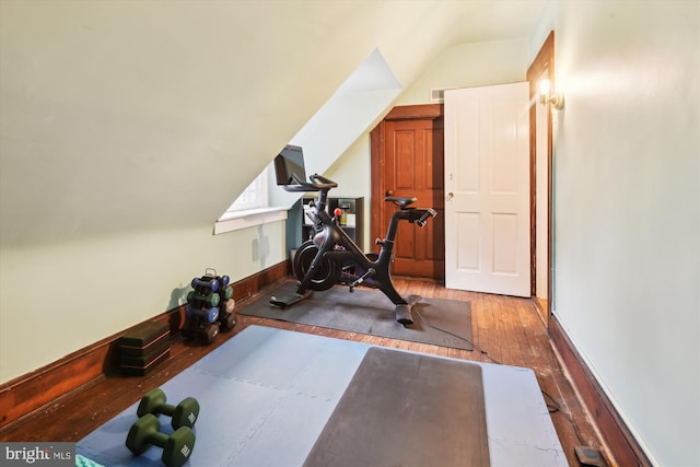 workout room with light wood-type flooring and vaulted ceiling