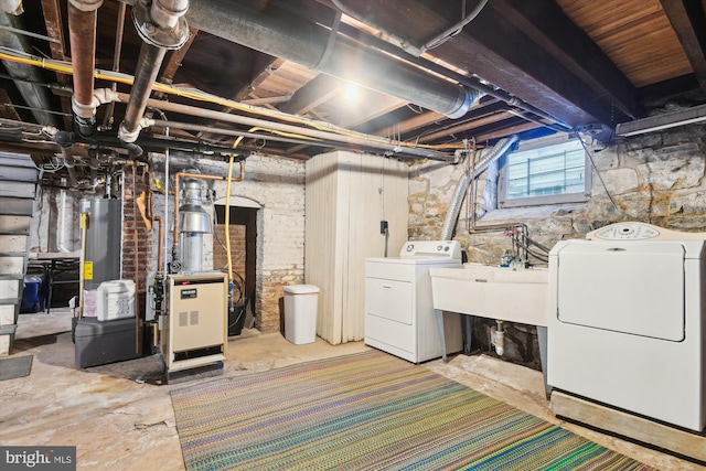 basement with sink, gas water heater, and separate washer and dryer