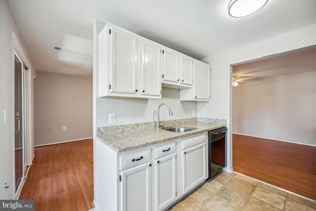 kitchen featuring light stone counters, sink, white cabinets, and black dishwasher