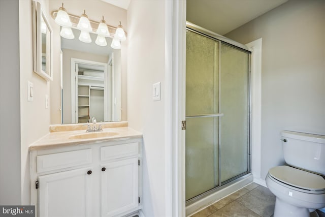 bathroom with vanity, a shower with shower door, tile patterned flooring, and toilet