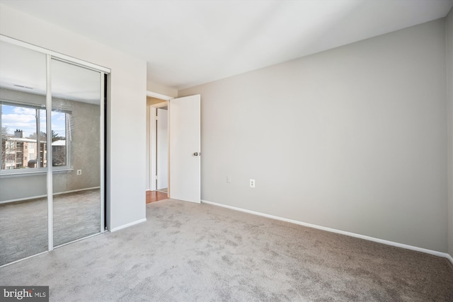 unfurnished bedroom featuring light colored carpet and a closet