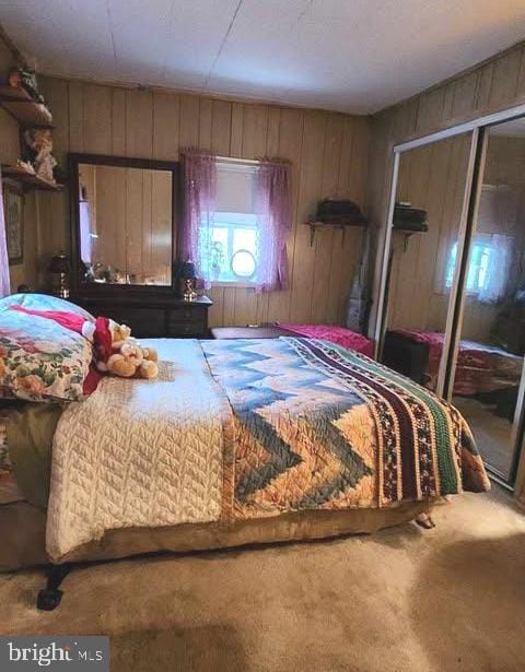 carpeted bedroom featuring a closet and wood walls