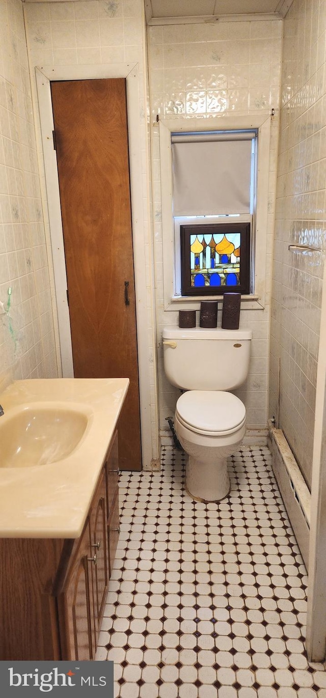 bathroom with toilet, tile walls, vanity, and a baseboard radiator