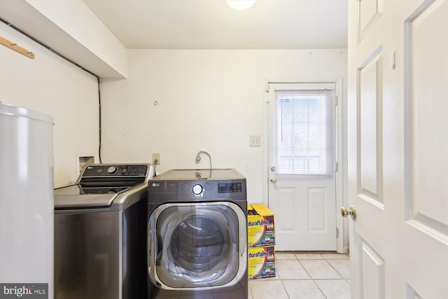 clothes washing area featuring light tile patterned flooring, water heater, and washing machine and dryer