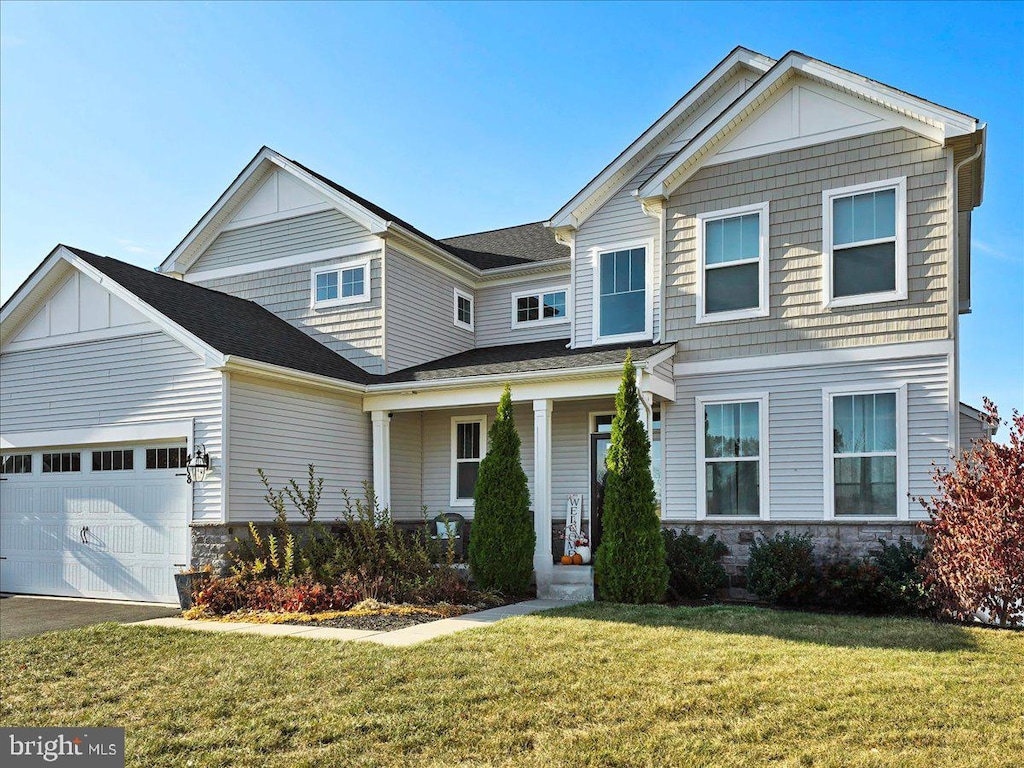 view of front of property with a garage, a front yard, and covered porch