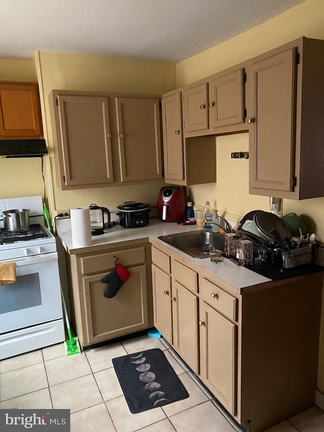 kitchen featuring light tile patterned flooring, sink, white range, and light brown cabinets