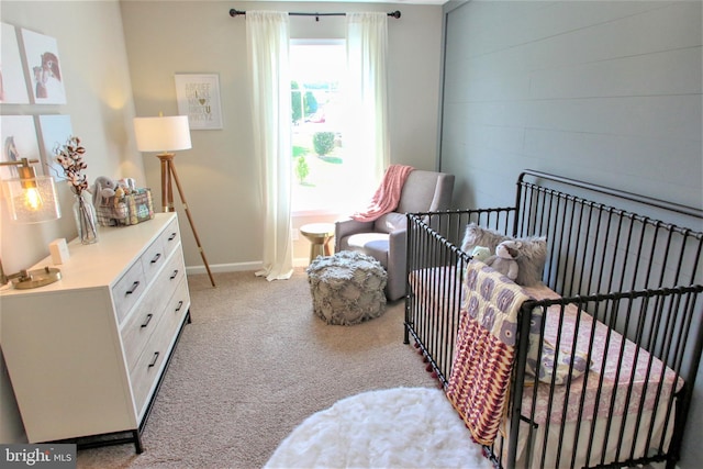 bedroom featuring light carpet and a nursery area