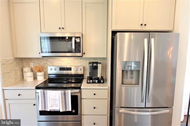 kitchen with decorative backsplash, light stone countertops, stainless steel appliances, and white cabinetry