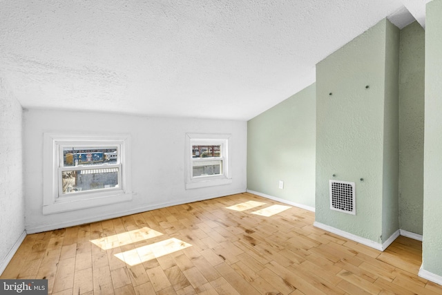 unfurnished living room featuring a textured ceiling and light hardwood / wood-style floors