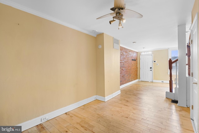 hall featuring light wood-type flooring, ornamental molding, and brick wall