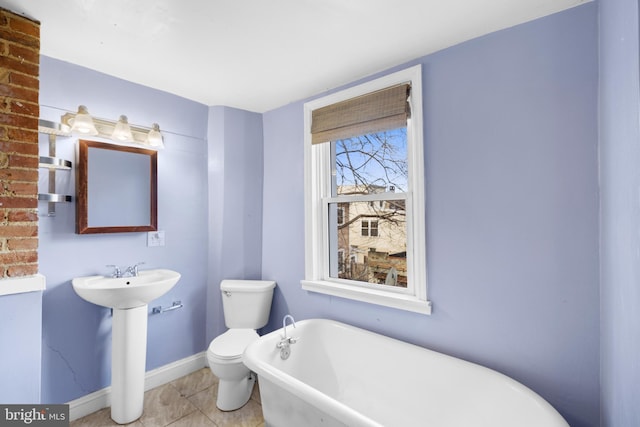 bathroom featuring tile patterned flooring, toilet, and a tub to relax in