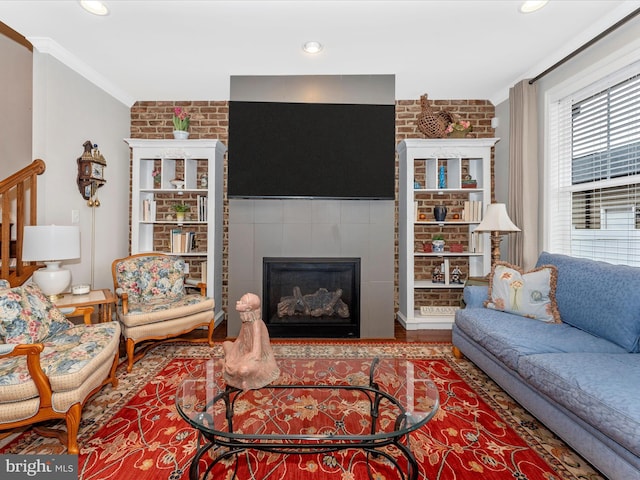 living room with hardwood / wood-style floors, crown molding, and brick wall