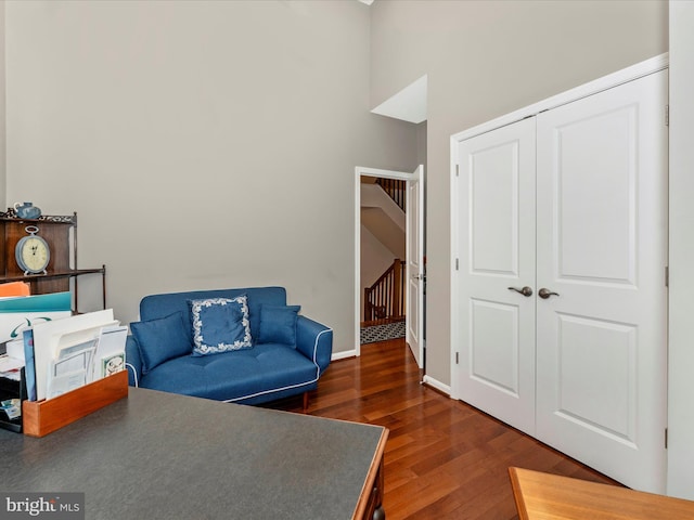 sitting room featuring a towering ceiling and dark hardwood / wood-style flooring