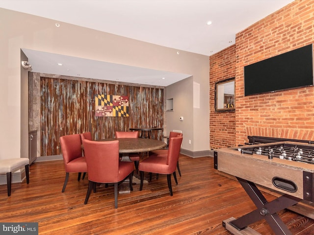 dining area featuring hardwood / wood-style flooring and brick wall