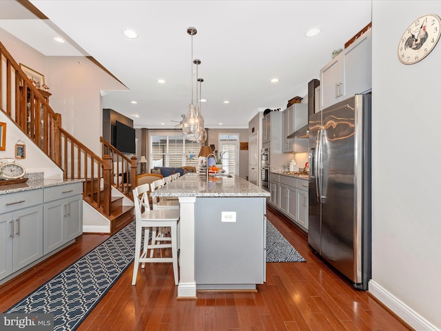 kitchen with a kitchen bar, gray cabinetry, a kitchen island, pendant lighting, and stainless steel appliances