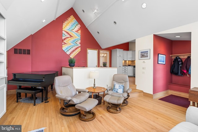 sitting room with high vaulted ceiling and light hardwood / wood-style floors