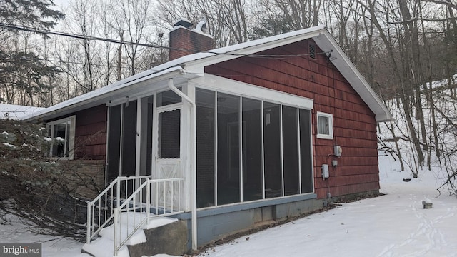 snow covered structure with a sunroom