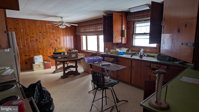 kitchen featuring ceiling fan, light colored carpet, white fridge, sink, and wooden walls