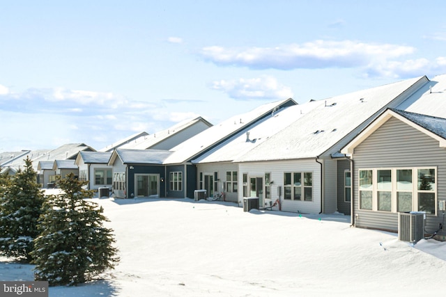 snow covered house featuring central AC