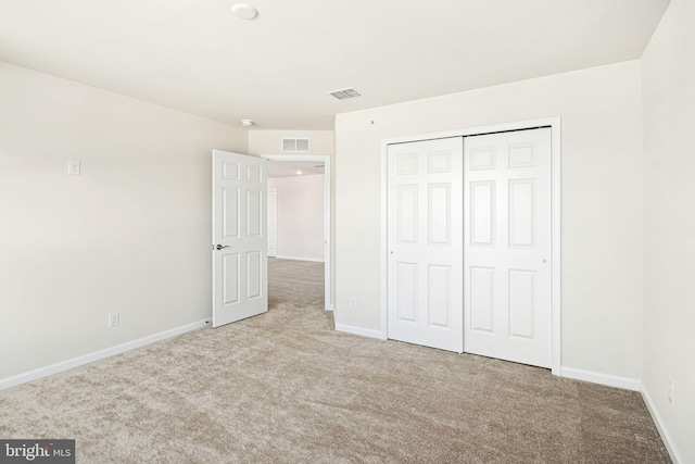 unfurnished bedroom featuring light colored carpet and a closet