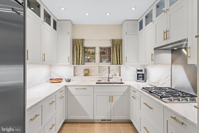 kitchen with appliances with stainless steel finishes, tasteful backsplash, sink, white cabinets, and light tile patterned floors