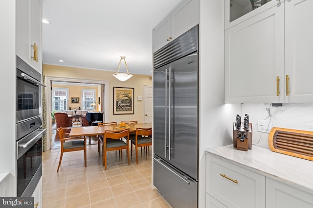 kitchen with pendant lighting, white cabinetry, light tile patterned floors, stainless steel appliances, and light stone countertops