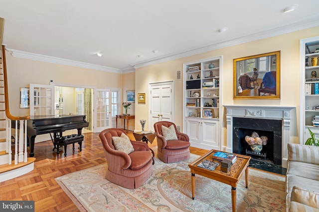 living room featuring light parquet floors, crown molding, a high end fireplace, and built in shelves