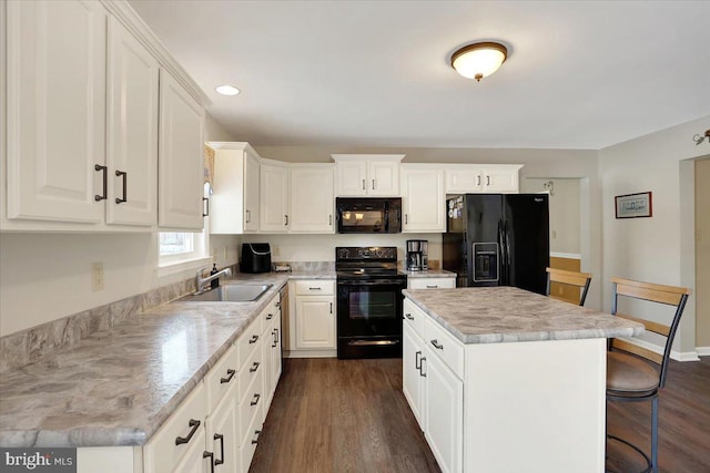 kitchen with sink, white cabinetry, a center island, a kitchen breakfast bar, and black appliances