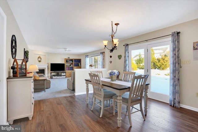 dining space featuring ceiling fan with notable chandelier and dark hardwood / wood-style flooring