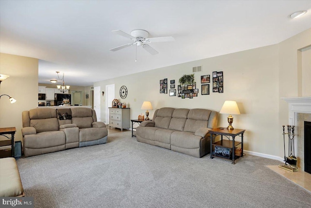 living room with ceiling fan with notable chandelier, a fireplace, and carpet floors