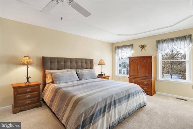 bedroom with multiple windows, ceiling fan, and light carpet