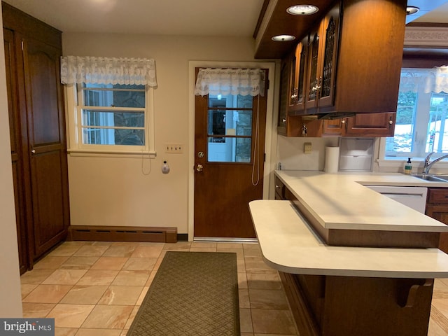 kitchen featuring dishwasher, light tile patterned flooring, sink, a kitchen breakfast bar, and a baseboard radiator