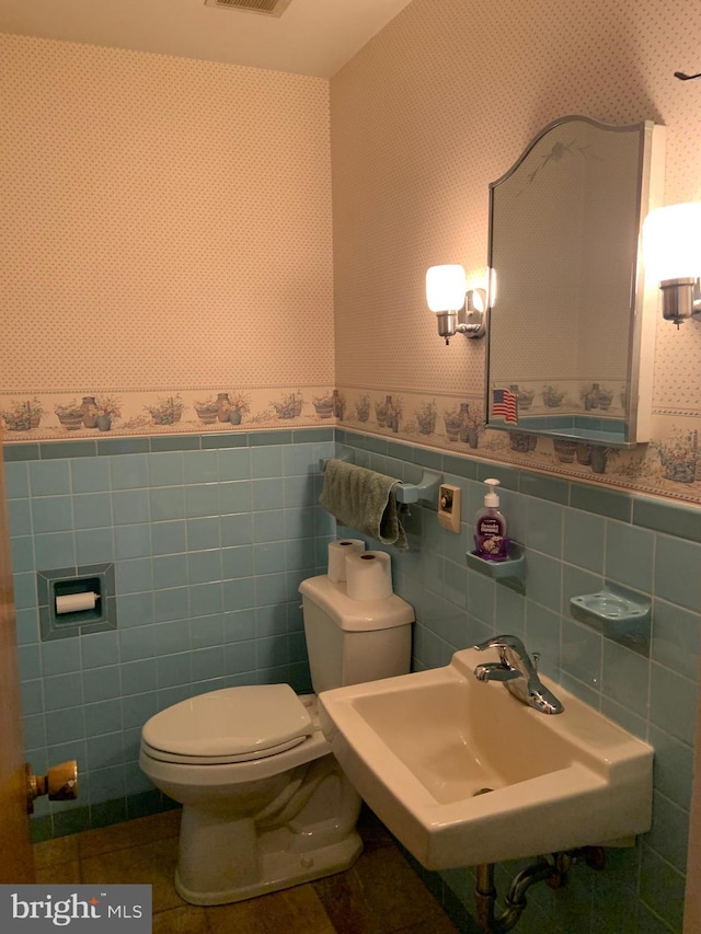 bathroom featuring toilet, tile walls, tile patterned floors, and sink