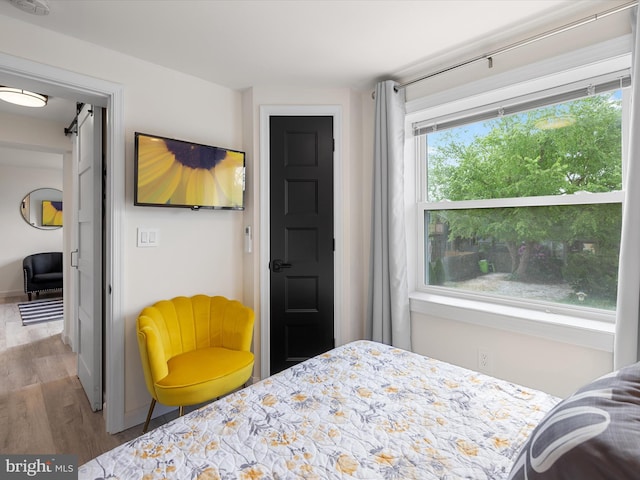 bedroom with a barn door and light wood-type flooring