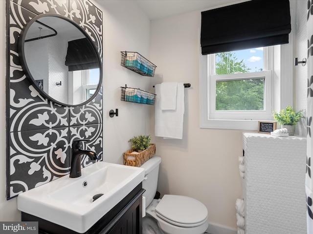 bathroom featuring toilet, a healthy amount of sunlight, and vanity